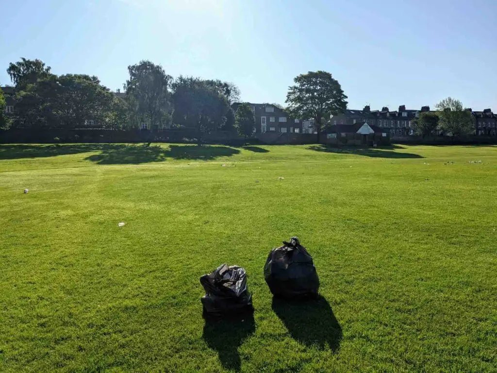 Plogging and picking up litter in black bags in the local park