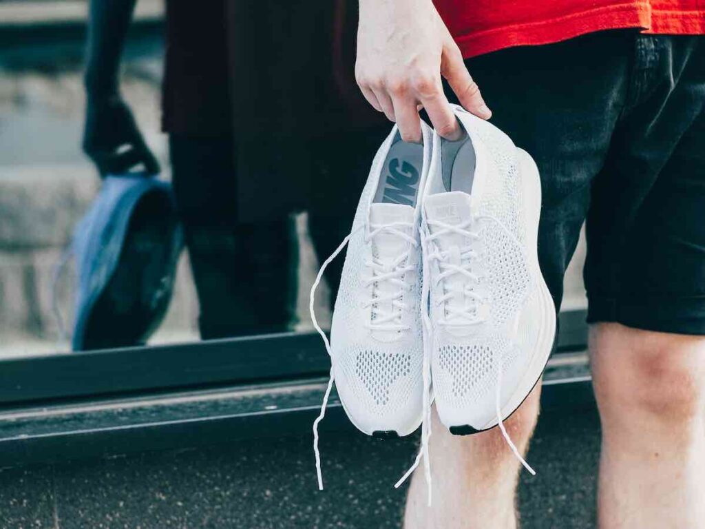 Athlete holding a pair of white running trainers