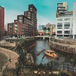 A yellow boat on the Leeds-Liverpool canal with skyscrappers in the background