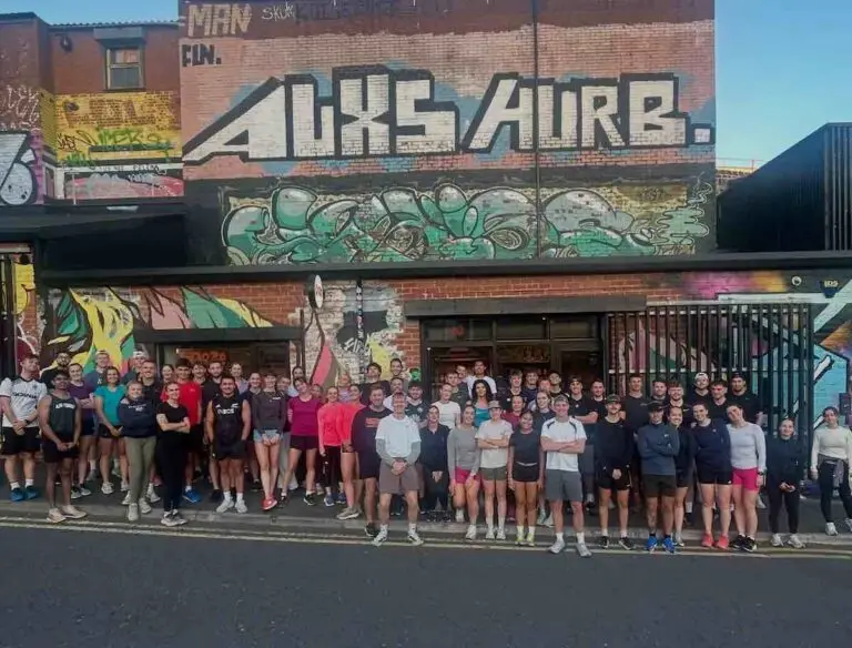 Group shot of Collective Run Club, against a graffiti wall in Ouseburn near Newcastle’s Quayside