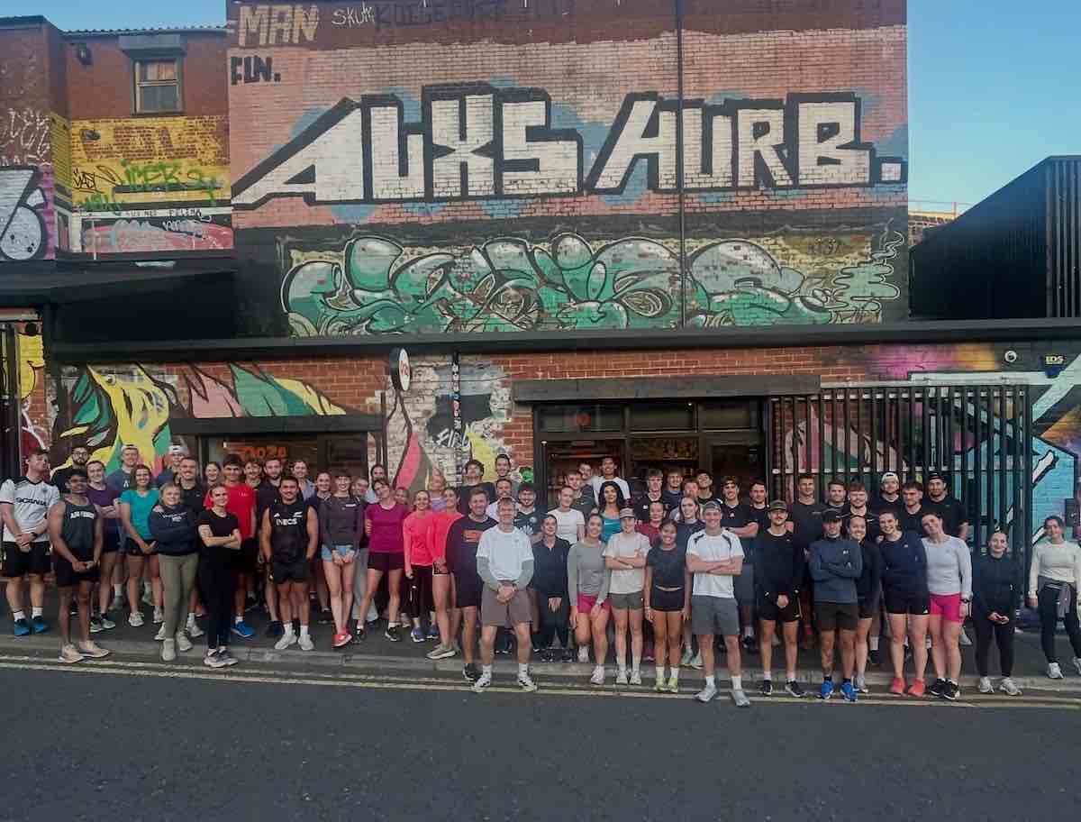 Group shot of Collective Run Club, against a graffiti wall in Ouseburn near Newcastle’s Quayside